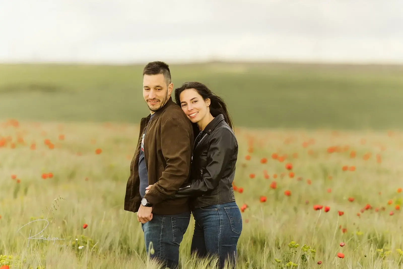 La pareja abrazada en un campo verde salpicado de amapolas