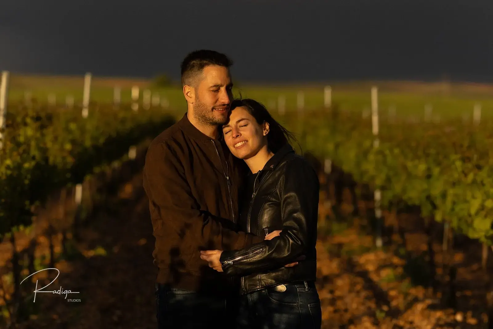 La pareja abrazada en el viñedo con un cielo de tormenta