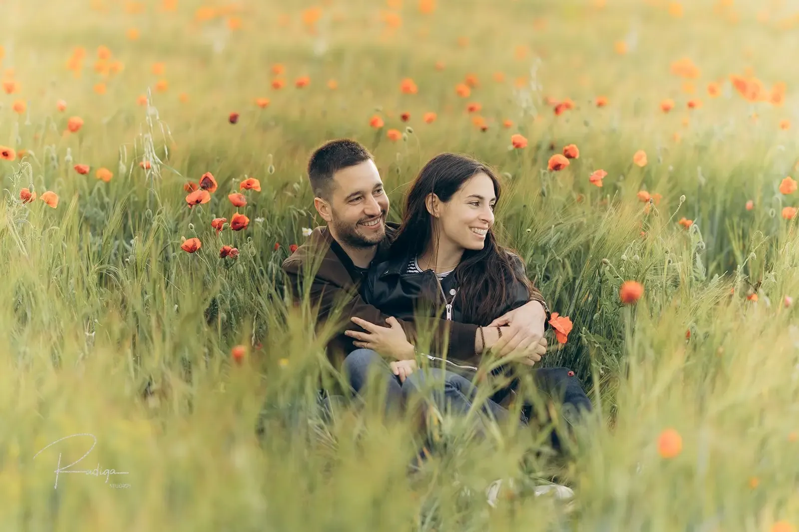 La pareja sentada entre la hierba alta y las amapolas