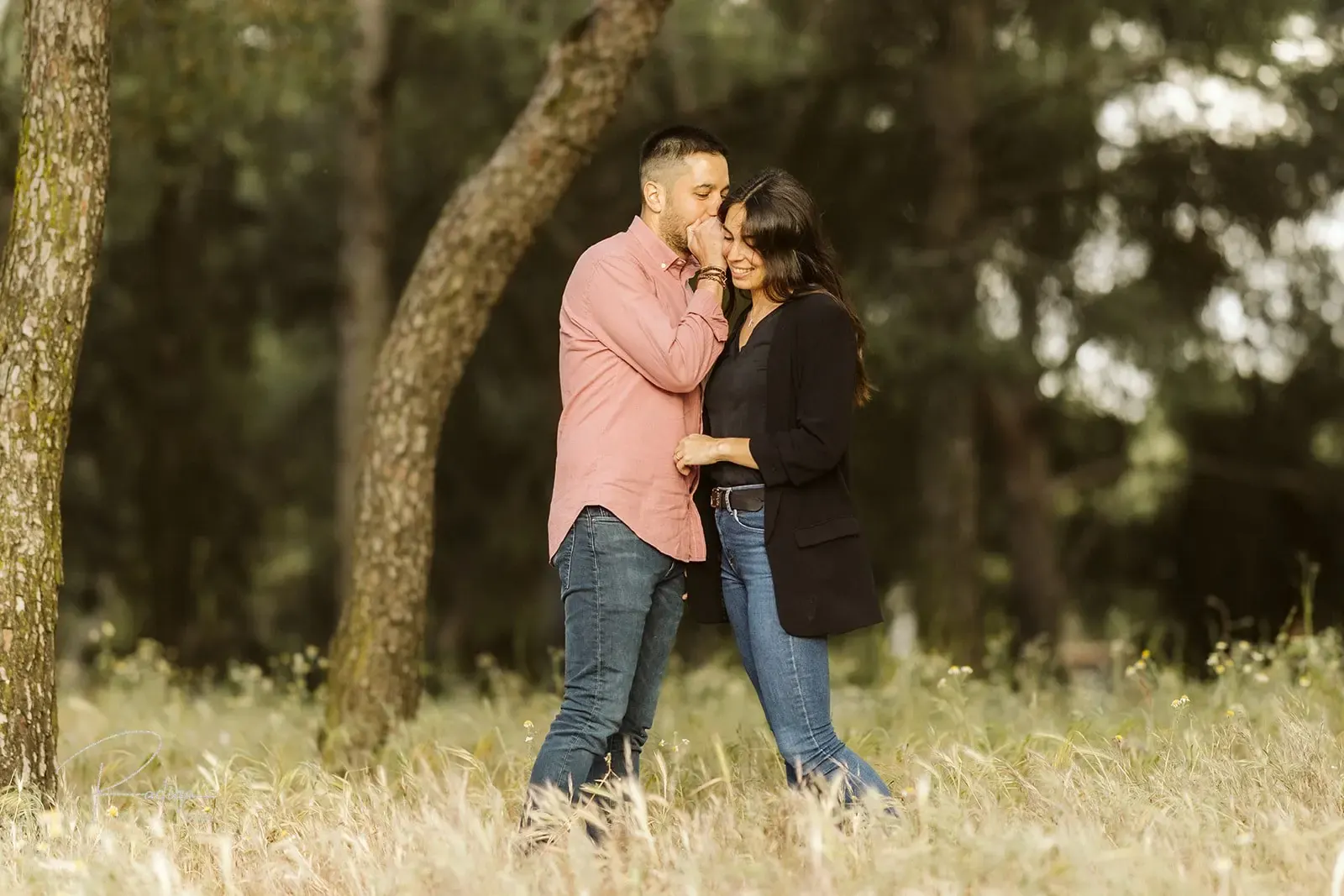 La pareja se besa entre los troncos de un pinar